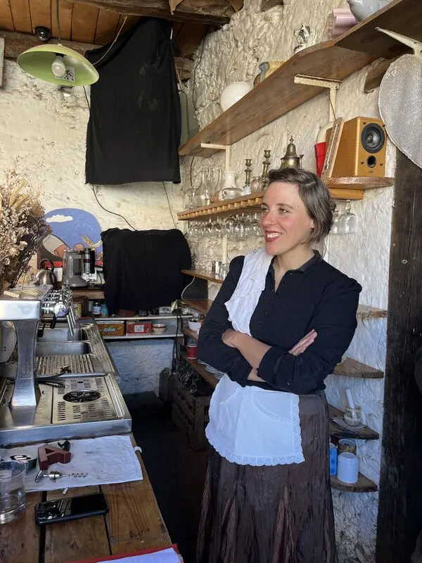 Une habitante en tablier blanc, derrière le bar du Café