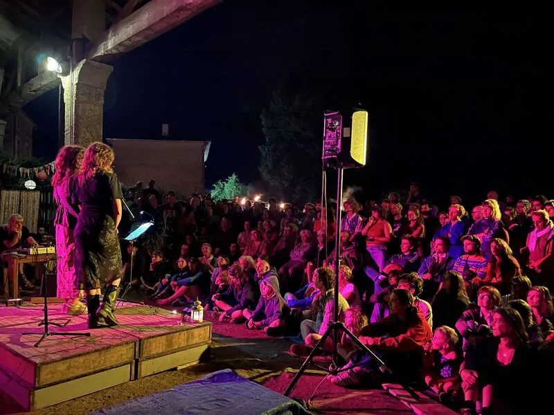 Concert de nuit, le public assis par terre devant la scène